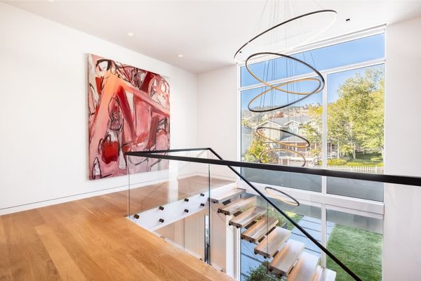 art on wall with floating staircase and modern chandelier